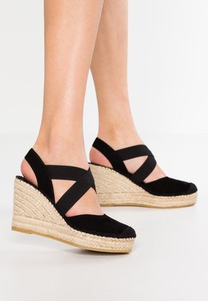 Sorte wedgesandaler lavet af ruskind med vævet jute-detalje. Har krydssamlede stropper og en struktureret, robust sål.