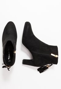 Zwarte suède enkellaarsjes met een spitse neus en een blokhak. Voorzien van een zijrits en een kwastdetail in goudkleurige hardware.