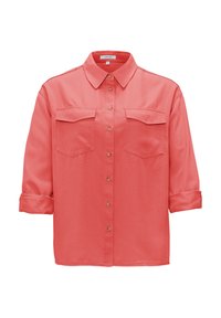 Chemise corail rose à manches longues avec boutons, deux poches poitrine et col pointu, manches retroussées jusqu’au milieu de l’avant-bras.