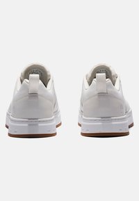 Baskets blanches avec une tige en cuir lisse et une semelle en caoutchouc gomme contrastante. Équipées d'un col rembourré et d'une languette pour un enfilage facile.