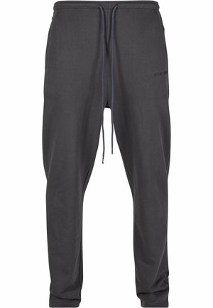 Mørkegrå joggebukser med snøring i midjen, smale ben og diskrete sidelommer. Stoffet ser mykt ut med en glatt tekstur.