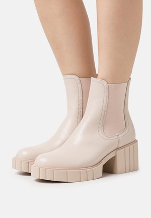 Beige leren enkellaarsjes met elastische zijkanten, stevige gestructureerde zolen en een ronde neus.