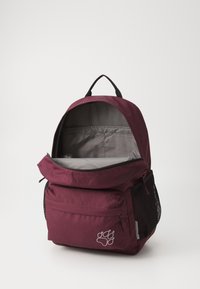 Bordo mugursoma ar priekšējo kabatu, acīm tīklu sānu kabatām un pelēku iekšpusi. Priekšpusē ir pēdas nospieduma logo. Ar rāvējslēdzēja aizdari.