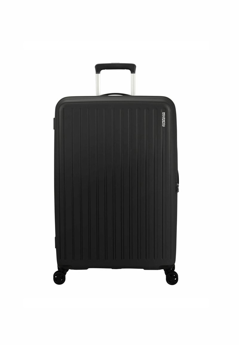 Valigia rigida nera con scanalature verticali, manico telescopico argentato e quattro ruote nere per la mobilità. Chiusura a zip sul lato.