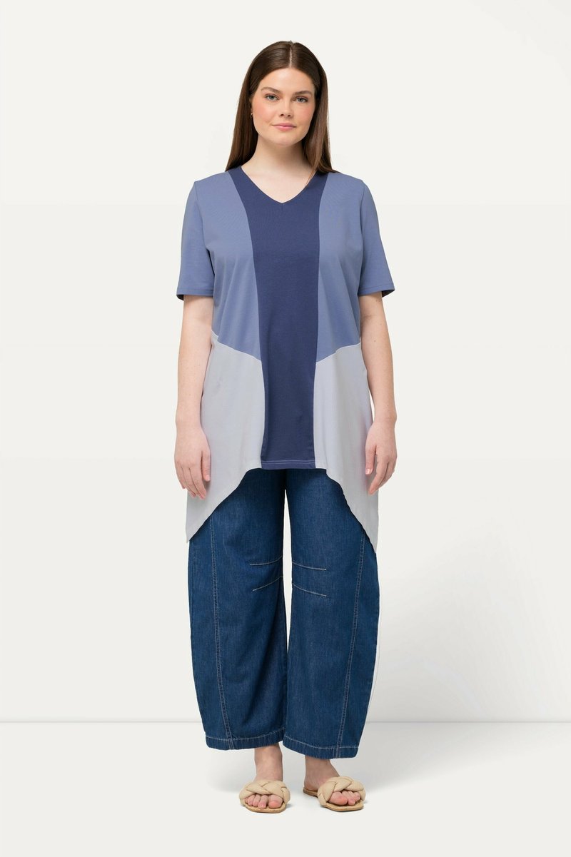 Kortärmad topp med en marinblå och ljusgrå färgblockdesign, med V-ringning och asymmetrisk nederkant; kombinerad med vida jeanstights.