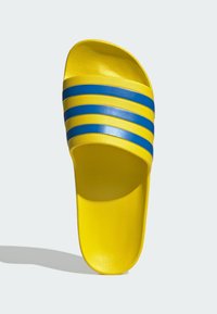 Sandalia de slide amarilla con un acabado texturizado, con tres franjas horizontales azules en la parte superior. Diseño abierto en la parte delantera. Ligera.