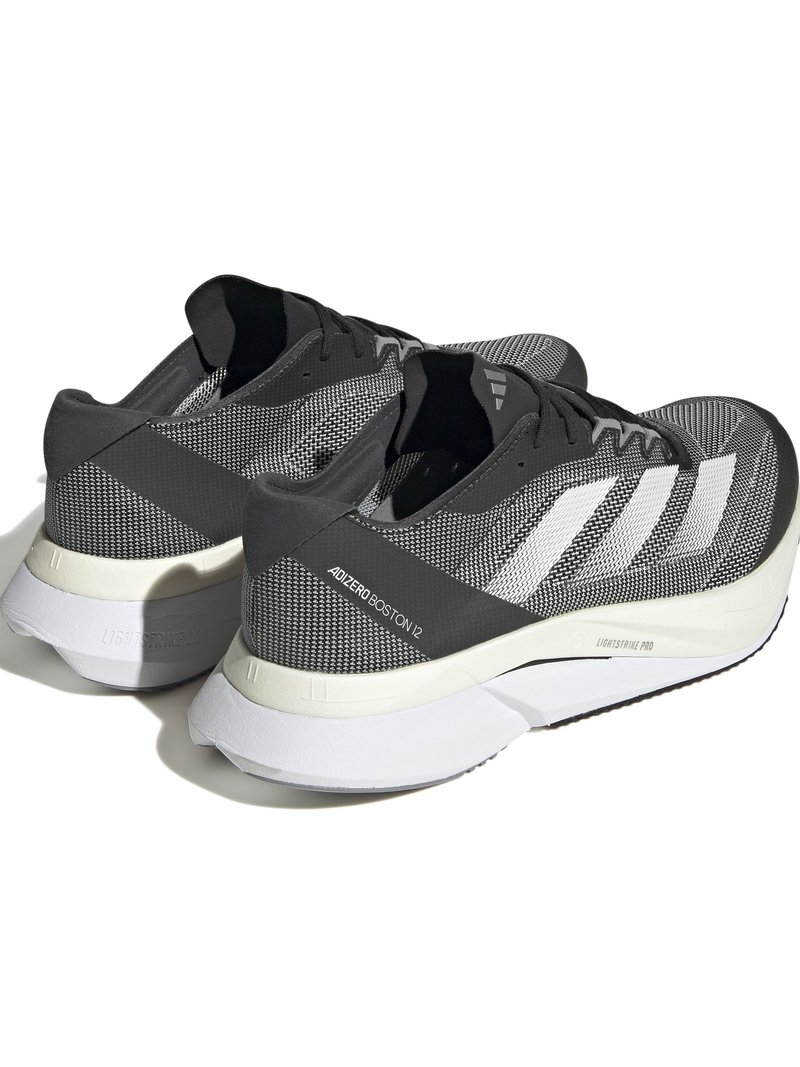Baskets de sport grises avec une tige en mesh respirant, des rayures blanches et une semelle rembourrée. Présente un motif texturé et un design léger.