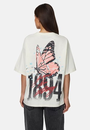 T-shirt blanc oversize arborant un papillon rose et noir avec des étoiles bleues et le texte audacieux "1894" en noir au dos.