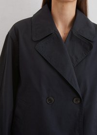 Marineblauer doppelt geknöpfter Mantel mit breitem Kragen, aus einem glatten Stoff gefertigt. Verfügt über zwei große schwarze Knöpfe und Seitentaschen.