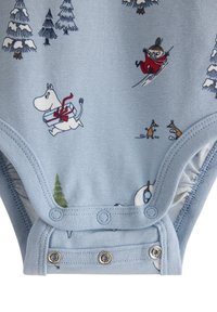 Lyseblå babybody med tegneseriefigurer, herunder et hvidt væsen, der bærer en gave, et barn, der står på ski, små dyr og sneklædte træer.