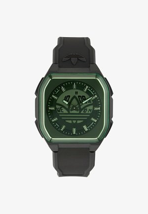 Čierne digitálno-analógové športové hodinky so štvorcovým zeleným rámikom, logom Adidas na ciferníku a gumovým remienkom s vyrazeným logom blízko hornej časti.