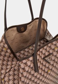 Sac à main brun à motifs avec des rayures diagonales, doté d'un intérieur beige et d'une marque. Comprend une fermeture à pression et deux anses.