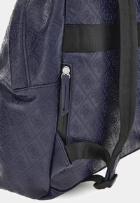 Zaino blu navy realizzato in materiale goffrato, con motivi trapuntati, spallacci neri regolabili e una tasca laterale con zip.