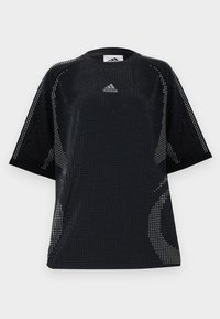 Camiseta deportiva negra de corte holgado, con diseño de malla, cuello redondo y logo sutil en el pecho. Textura perforada en toda la prenda.