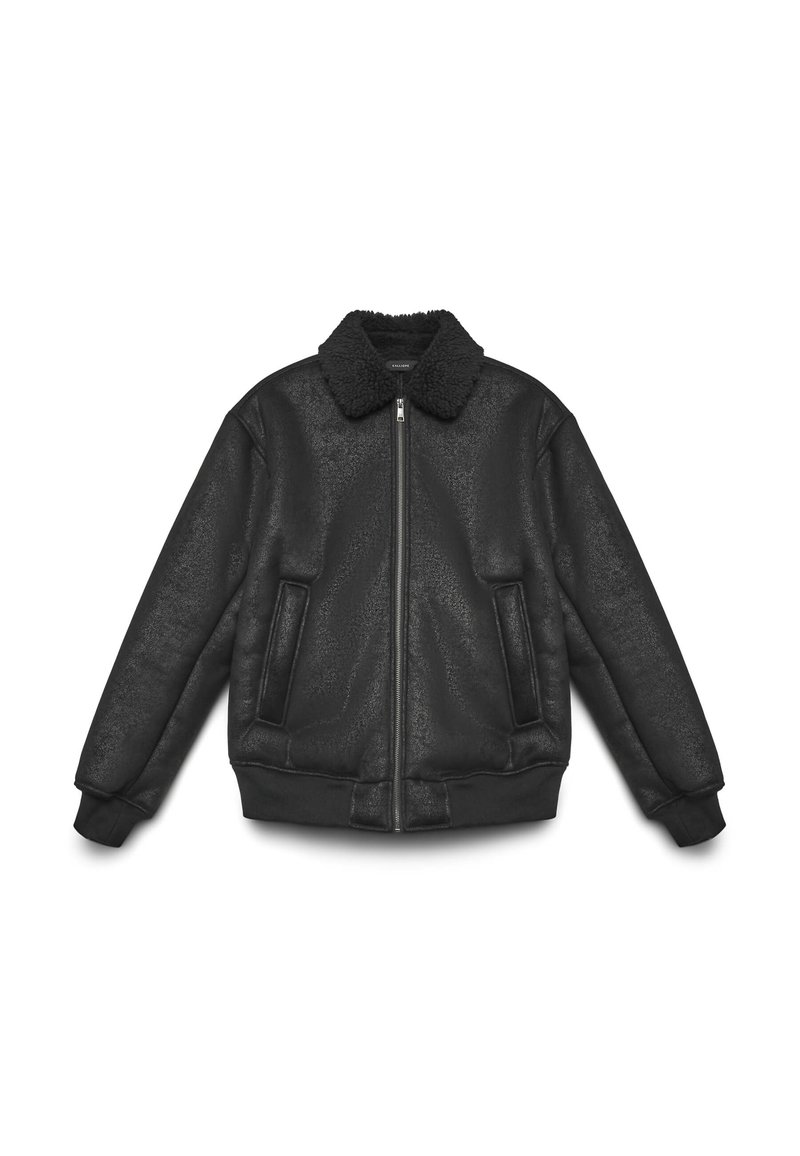 Giacca bomber in ecopelle nera con colletto peloso, due tasche frontali, polsini a costine e chiusura con zip. Texture liscia.