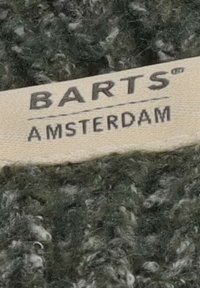 Etichetta con la scritta "BARTS AMSTERDAM" attaccata a un tessuto lavorato a maglia di colore verde scuro.