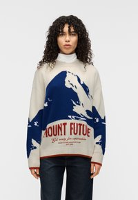 Πλεκτό πουλόβερ σε κρεμ απόχρωση με μπλε γραφικό βουνού, διακοσμημένο με τολμηρό κόκκινο κείμενο «MOUNT FUTURE» και έντονα ριμπ μανσέτες και τελείωμα.
