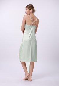 Rochie din satin verde mentă, cu un croi până la genunchi, dotată cu un design la spate cu bretele, o ușoară decupare pe lateral și o textură netedă.