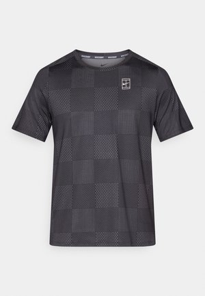 Camiseta negra de manga corta con un patrón cuadriculado que presenta diversas texturas, incluyendo rayas y puntos. Incluye un pequeño logo en el pecho.