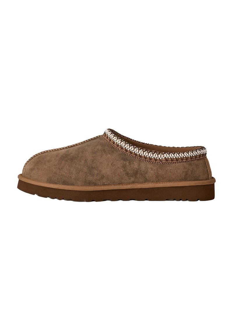Zapato marrón de ante tipo slip-on con punta redonda, parte superior texturizada y un acento trenzado alrededor del cuello. Presenta una suela de goma plana.