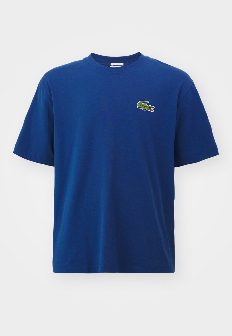 T-shirt bleu à manches courtes avec col rond et petit logo crocodile vert sur le côté gauche de la poitrine.