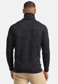 Dunkelgrauer Kabelstricksweater mit hohem Kragen, strukturierten Ärmeln und solidem Körper, aus einer weichen Wollmischung gefertigt.