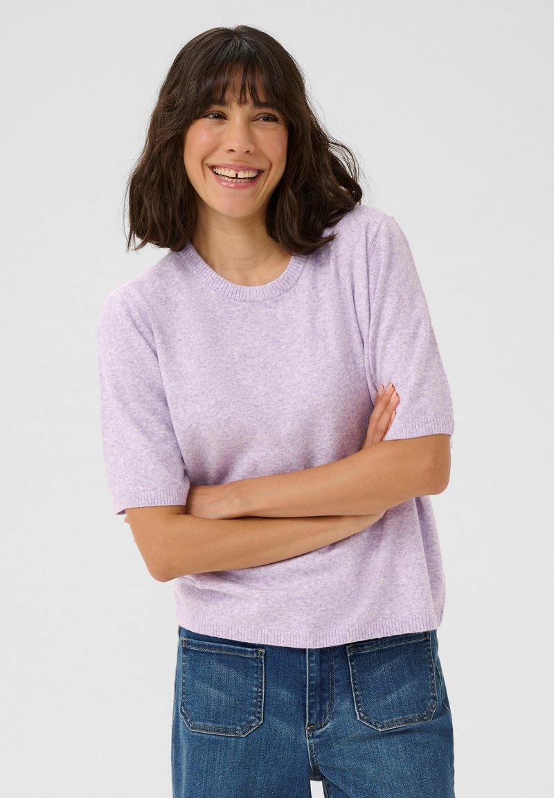 Pull en tricot lilas à manches courtes avec un col rond, texture douce et poignets côtelés. Associé à un jean en denim bleu.