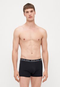 Black cotton boxer briefs with a white "PIER ONE" logo waistband. The fabric appears soft with a smooth texture. The fit is snug, designed for men.