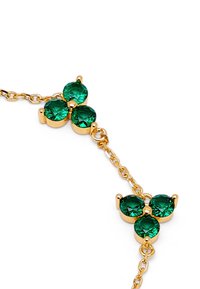 Collar de cadena de oro con tres piedras preciosas verdes redondas dispuestas en forma triangular, con un acabado de metal pulido.