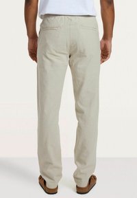 Lichtbeige broek gemaakt van een gestructureerde stof met een relaxte pasvorm. Kenmerkt zich door een elastische tailleband en twee achterzakken.