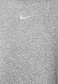 Szary sweatshirt wykonany z miękkiego, teksturowanego materiału. Posiada małe, białe logo Nike wyszyte na klatce piersiowej. Krój z okrągłym dekoltem.