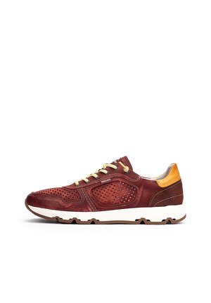 Zapatillas de cuero rojo con paneles perforados, cordones beige y un acento en el talón de color marrón claro. Suela blanca gruesa con grabado.