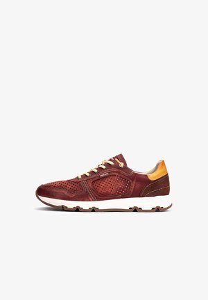 Zapatillas de cuero rojo con paneles perforados, cordones beige y un acento en el talón de color marrón claro. Suela blanca gruesa con grabado.