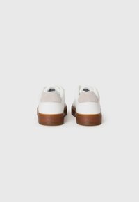 Witte sneakers met een glad leren bovenwerk, grijze suède accenten op de hiel en een bruine rubberen zool met geperst merklogo.