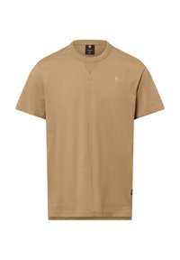 Camiseta de manga corta en un color beige claro, hecha de una tela suave. Presenta un cuello redondo y un pequeño logo bordado en el pecho.