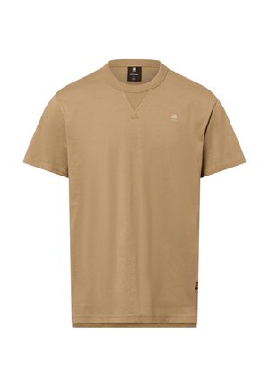 T-shirt à manches courtes de couleur beige clair, en tissu doux. Dispose d'un col rond et d'un petit logo brodé sur la poitrine.