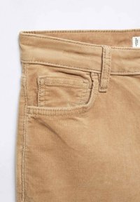 Ceinture de pantalon en velours côtelé marron clair avec passants de ceinture, poche avant et petite poche à monnaie sur fond blanc.