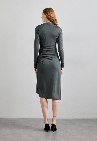 Long-sleeve dress in dark gray jersey fabric, featuring a fitted silhouette, gathered details along the back, and a midi length.