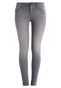 Jeans skinny de denim gris con una textura suave, diseño de cinco bolsillos y cierre de botón y cremallera. Acabado deslavado a lo largo de las piernas.