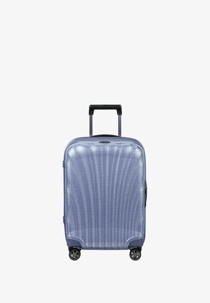 Hard-shell suitcase in light blue, featuring a textured surface with vertical lines, retractable handle, and four spinner wheels.