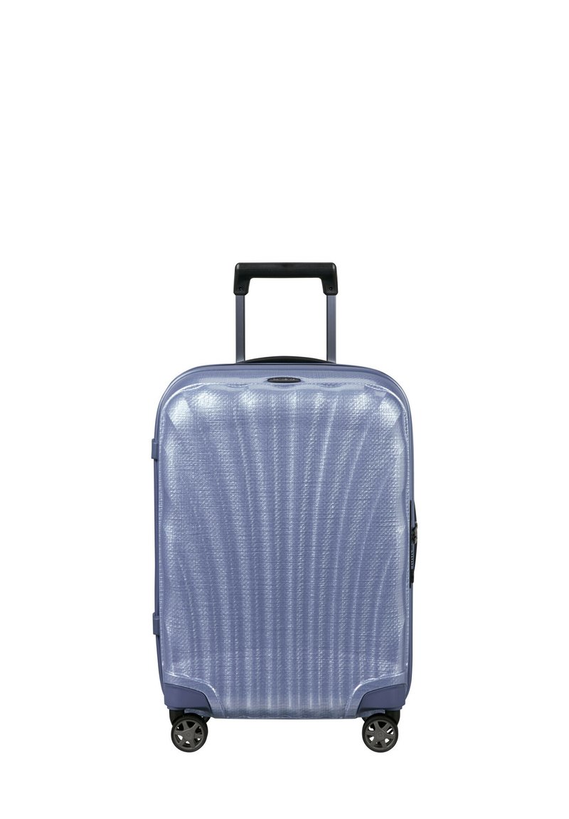 Hard-shell suitcase in light blue, featuring a textured surface with vertical lines, retractable handle, and four spinner wheels.