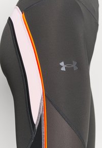 Czarne legginsy z wysokim stanem, z różowymi i pomarańczowymi akcentami po bokach, siateczkowymi detalami i szarym logo Under Armour, o gładkiej fakturze.