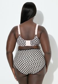 Rintaliivit ja korkeavyötäröiset alushousut vaaleanpunertavalla pohjalla mustilla pilkuilla. Rintaliiveissä leveät olkaimet ja hakaskiinnitys; alushousuissa sileä, läpikuultava materiaali.