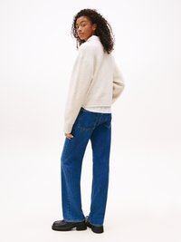 Cream ribbed sweater, wide-legged blue jeans, and black platform shoes. The sweater has a cozy, soft texture and oversized fit.
