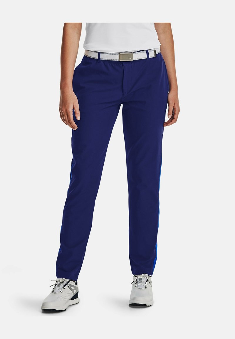 Mörkblå byxor med rak passform, som har ett kontrasterande ljusblått stripe på sidorna och ett vitt bälte. Bärs med grå sneakers.