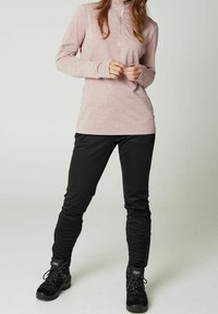 Lyserød langærmet top med kvartlynlås og tekstureret mønster, kombineret med tætsiddende sorte bukser og sorte vandrestøvler.