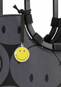 Zwarte tote bag met een smiley face label, met een gestructureerd oppervlak en een ontwerp van donkergrijze abstracte vormen.