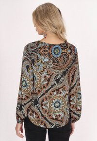 Blusa a maniche lunghe nera con intricati motivi paisley caratterizzati da dettagli blu e arancioni, scollo tondo e vestibilità rilassata.