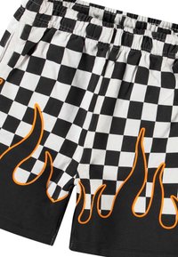 Shorts à carreaux noir et blanc avec des accents de design en flammes orange sur les bords inférieurs. Taille élastique, en coton.