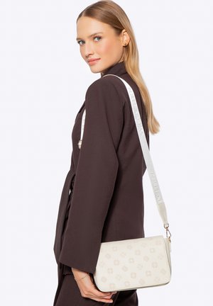 Witte crossbodytas met geperste bloemmotieven en een gestructureerde afwerking. Voorzien van een lichte riem met de merknaam erop gedrukt.